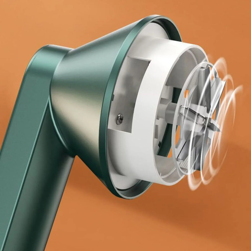 Close-up of a green handheld lint remover with rotating blades on an orange background