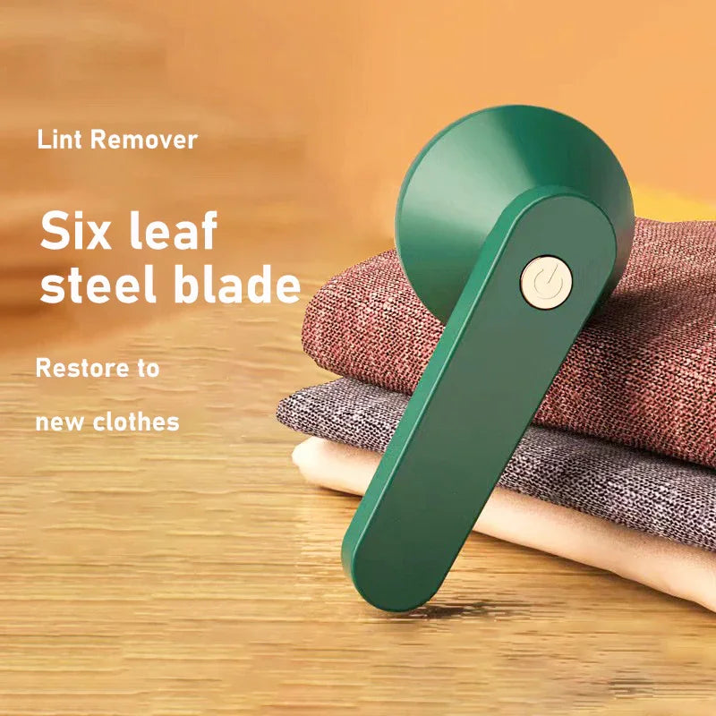 Green electric lint remover with six-leaf steel blade on folded clothes, home gadget.