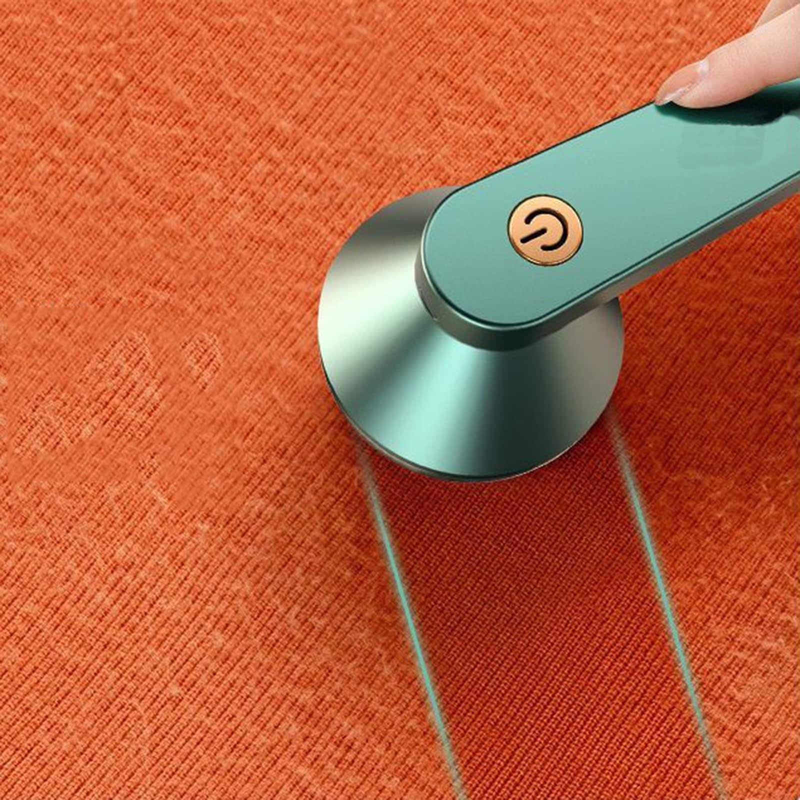 Handheld electric lint remover cleaning orange fabric surface